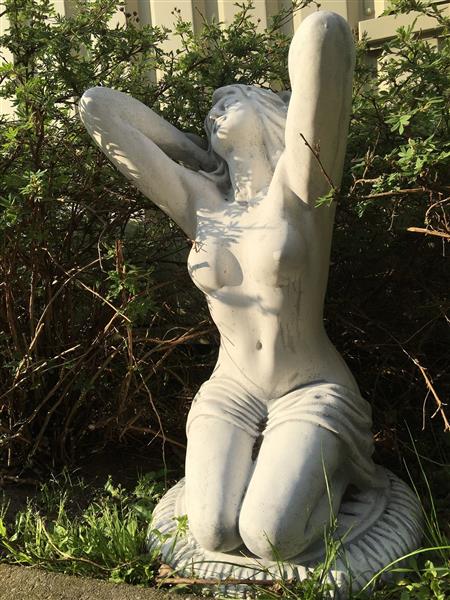 Grote foto mooi vol stenen beeld van een naakte knielende vrouw heel fraai tuin en terras tuindecoratie